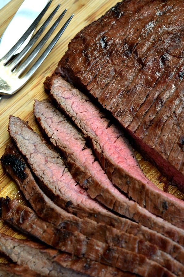 Grilled Flank Steak on a cutting board half cut into strips