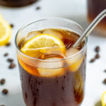 Pinterest Pin for Coffee Lemonade with a glass of coffee with ice, lemon slices, and a metal straw