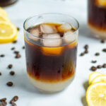 Coffee Lemonade Pinterest Pin showing a glass with lemonade layered on the bottom and iced coffee on top with ice cubes
