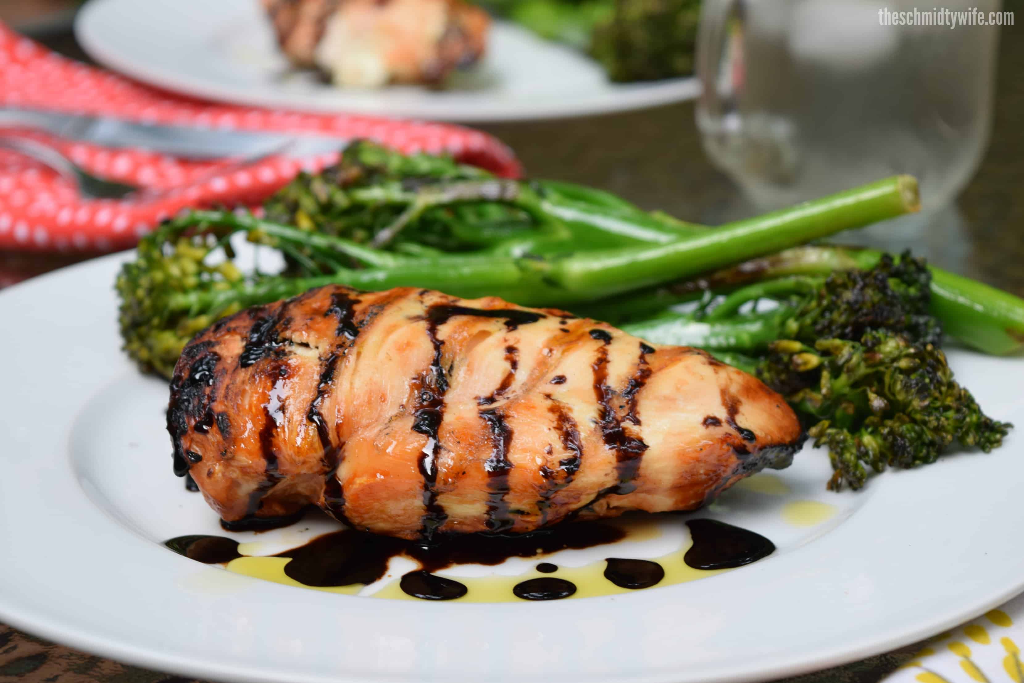 Stuffed Caprese Chicken grilled to perfection and sitting on a plate with broccolini 
