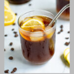 Pinterest Pin for coffee lemonade showing a photo of a glass of coffee with ice and a lemon wedge with a metal straw