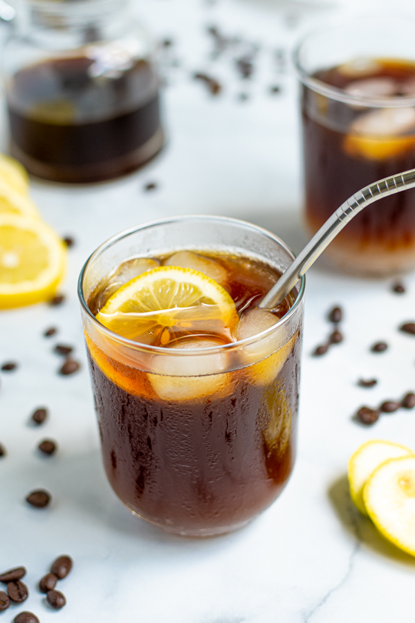 a glass of coffee lemonade with ice and a lemon slice