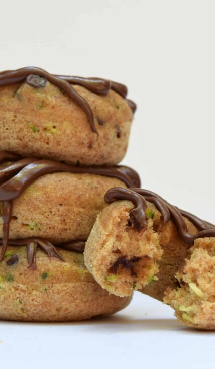 stack of 3 baked zucchini donuts and a 4th donut with a bite taken out of it