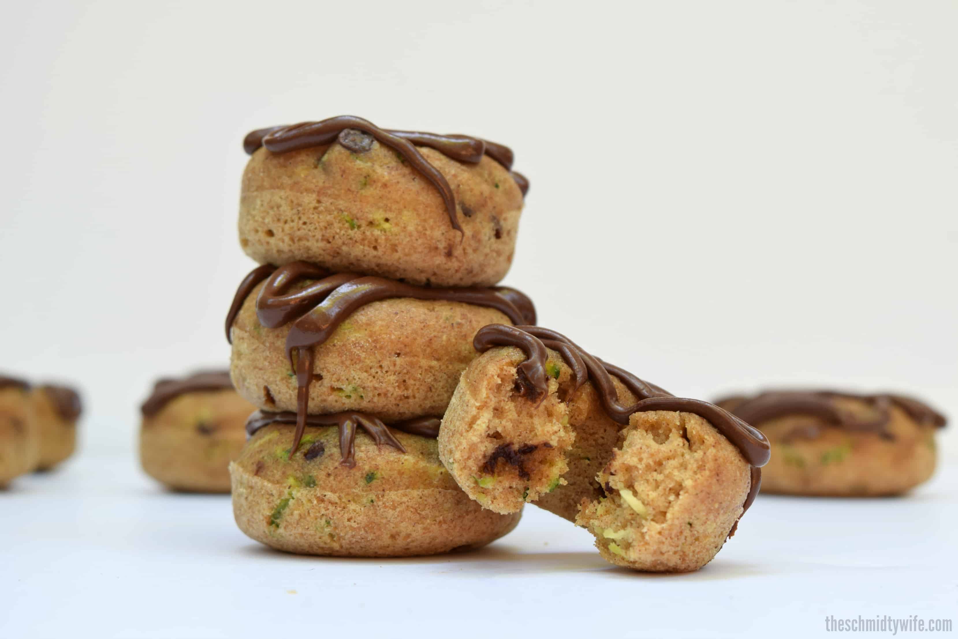 stack of 3 baked zucchini donuts and a 4th donut with a bite taken out of it