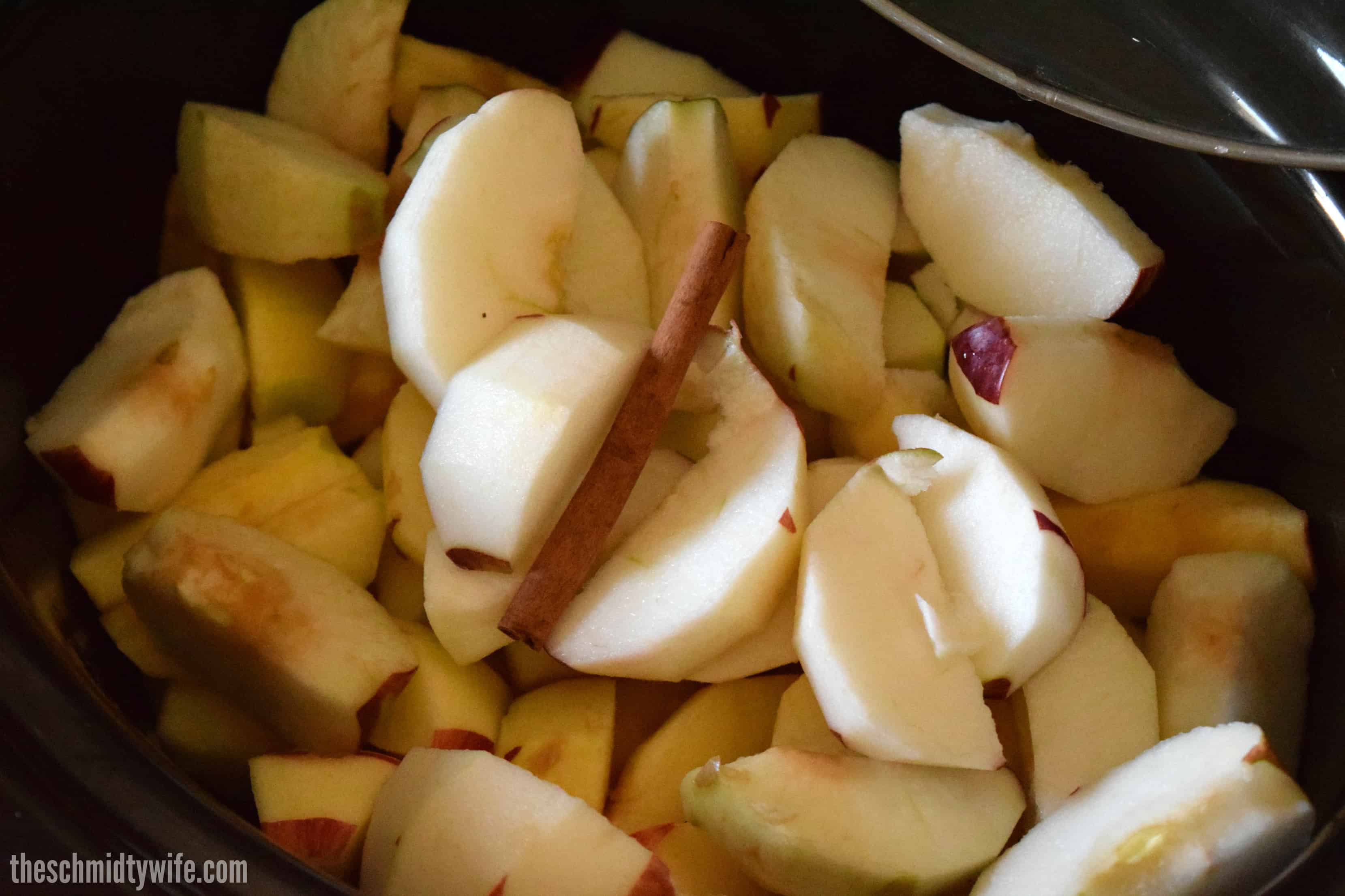 sliced apples with a cinnamon stick in the crockpot