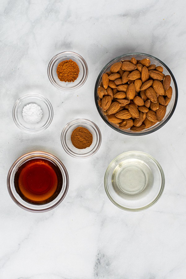 simple ingredients needed to make spicy candied almonds, raw almonds, cinnamon, cayenne, oil, maple syrup, and salt