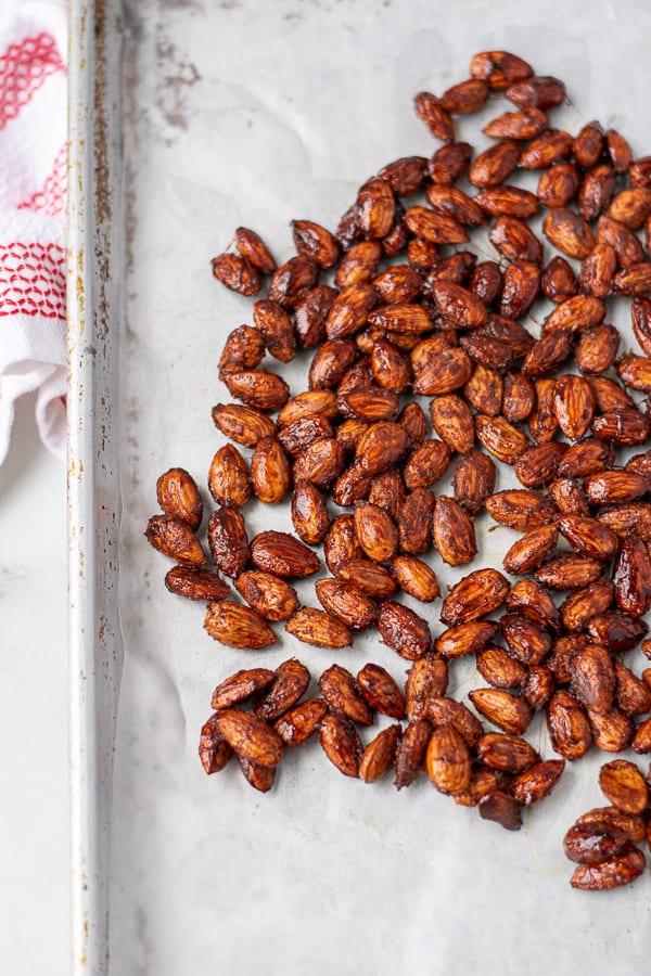 candied almonds spread out on a lined sheet pan