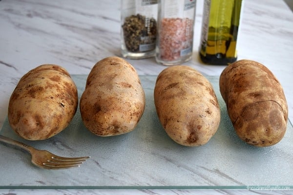 4 potatoes sitting on a cutting board