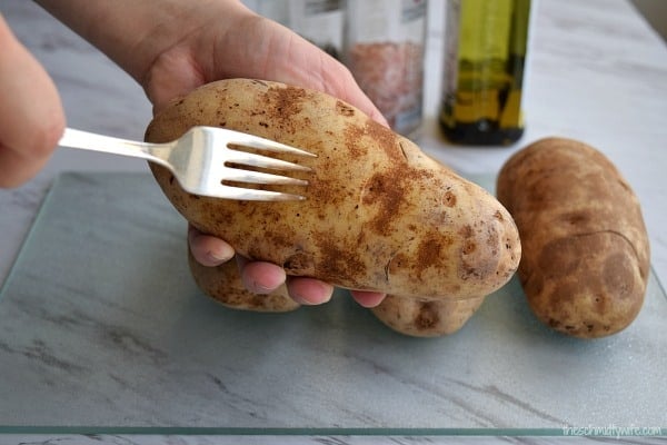 fork poking little holes into a potato to get it ready for the oven