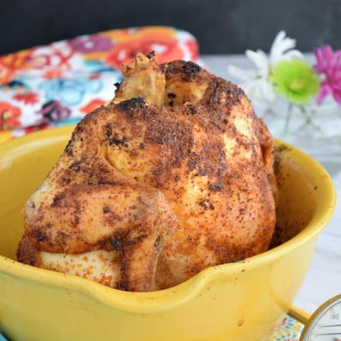 a crispy roasted chicken in a yellow roasting container