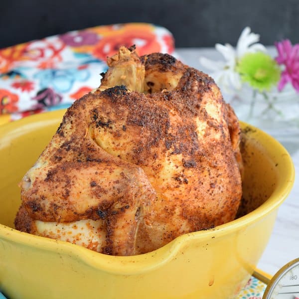 a crispy roasted chicken in a yellow roasting container