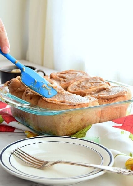 spatula spreading date caramel onto yeast whole wheat rolls