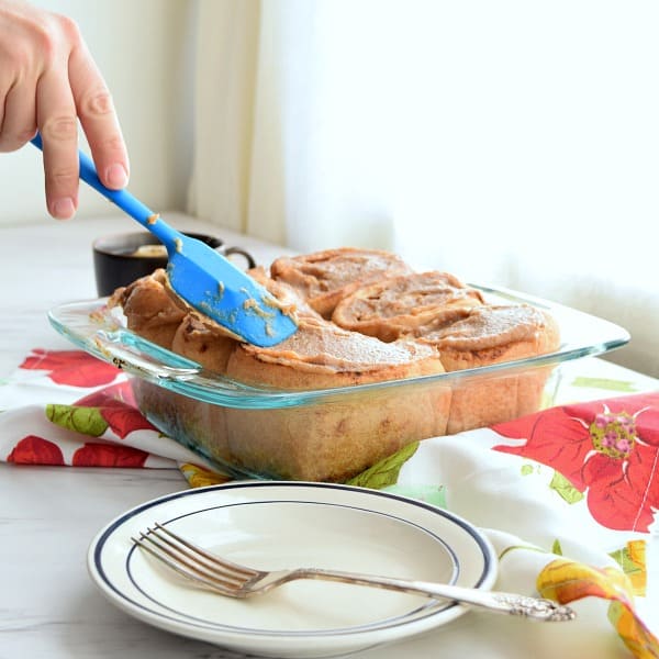 spatula spreading date caramel onto yeast whole wheat rolls