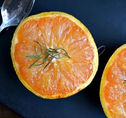 Honey Broiled Grapefruit on a black plate with a spoon