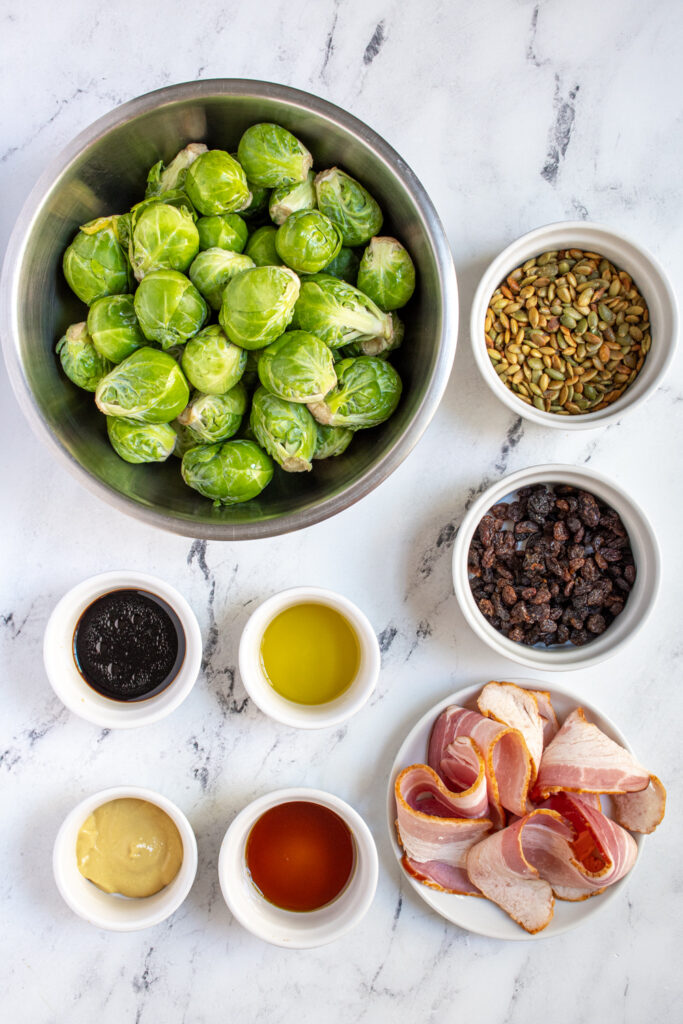 All the ingredients to make Balsamic Brussel Sprout Salad laid out on a tabletop.