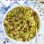 Pinterest Pin with text 'Warm Balsamic Brussel Sprout & Bacon Salad', image of a serving bowl full of shaved brussel sprout salad with bacon, raisins, and pumpkin seeds.