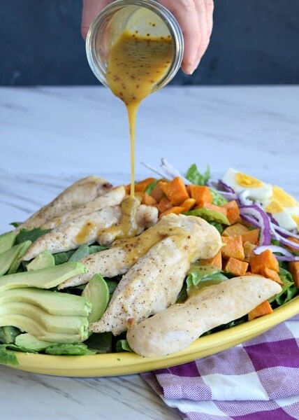 Honey Mustard Dressing being poured onto the salad