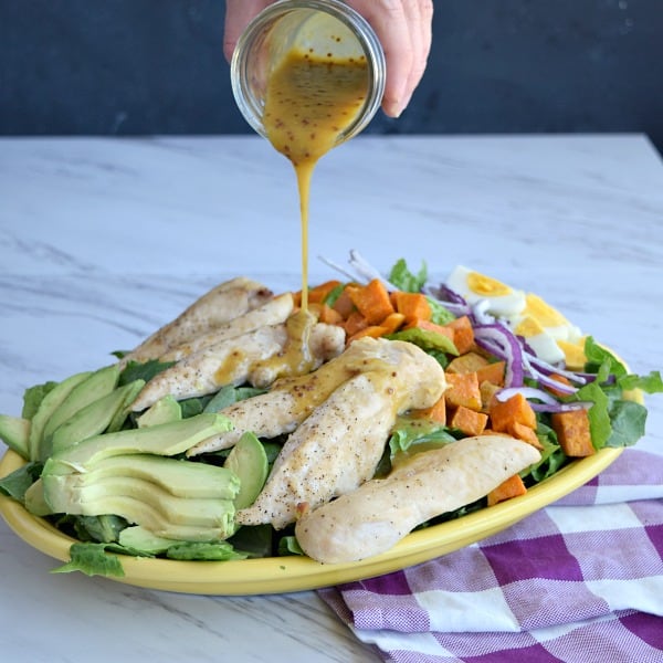 Honey Mustard Dressing being poured onto the salad