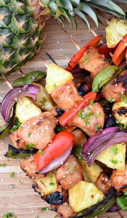 Grilled Pineapple Chicken Kabobs on a bamboo board with a pineapple