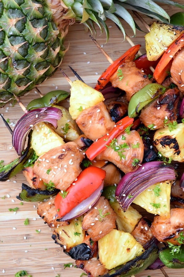 Grilled Pineapple Chicken Kabobs on a bamboo board with a pineapple