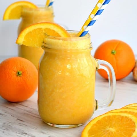 2 orange ginger sunshine smoothies with oranges and orange slices
