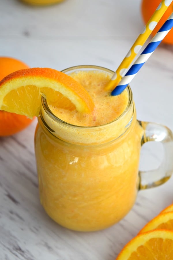 close up top view of orange ginger smoothie with an orange wedge