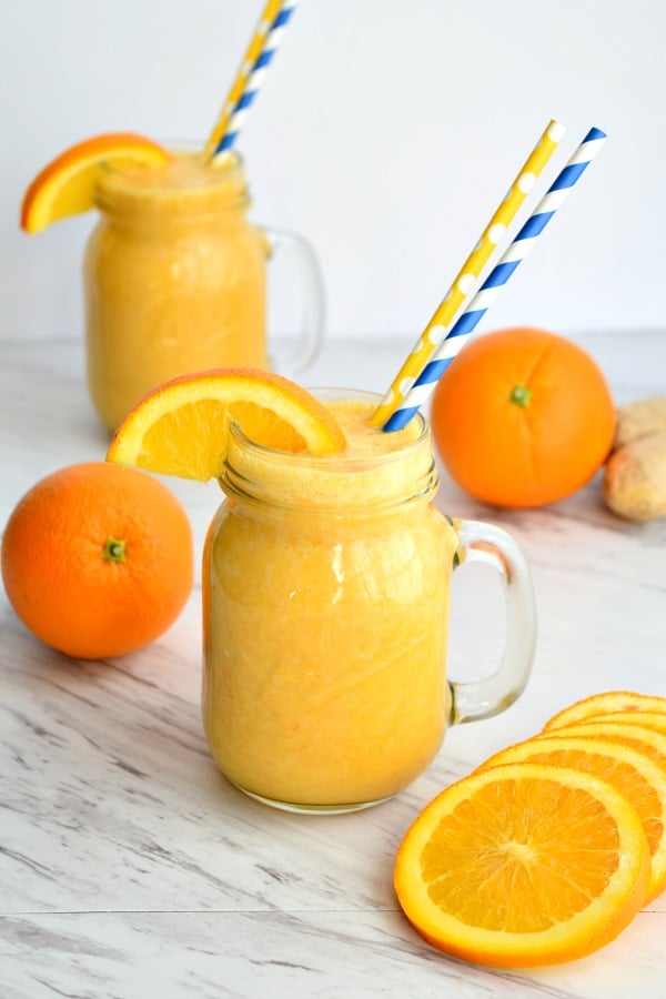 orange ginger smoothie with orange wedges and straws
