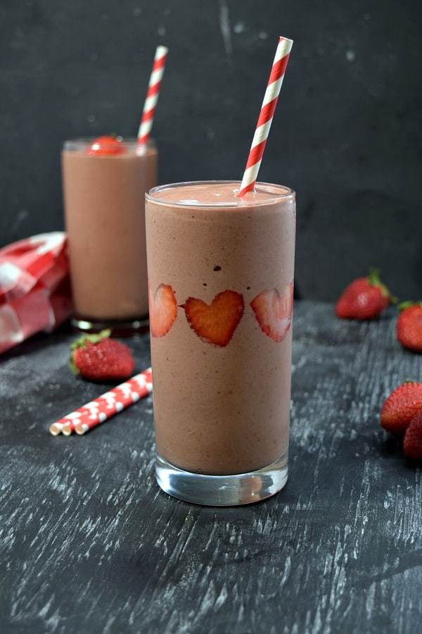 strawberry chocolate smoothie with heart shaped strawberries stuck in the side