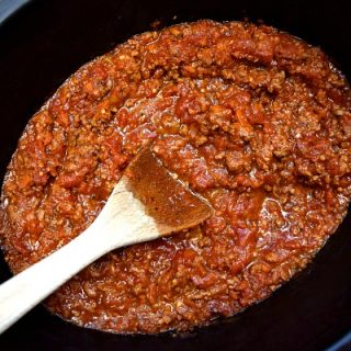 close up view of bolognese sauce in the crockpot with a spoon