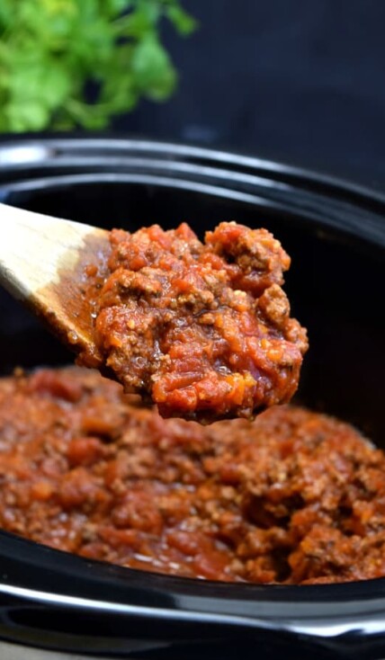 a large spoon full of bolognese sauce over top a crockpot