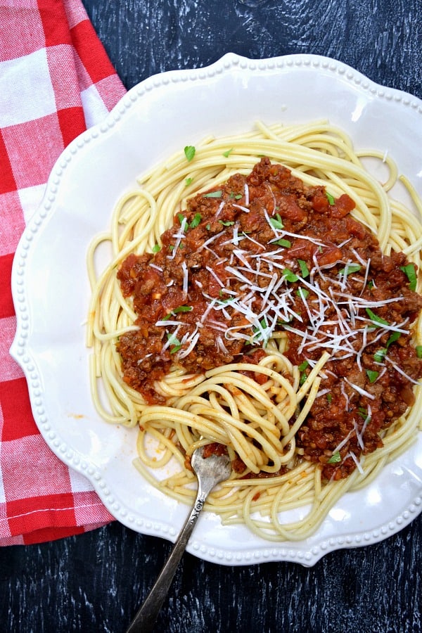 overhead shot of crockpot bolognese over noodles spun in a fork 
