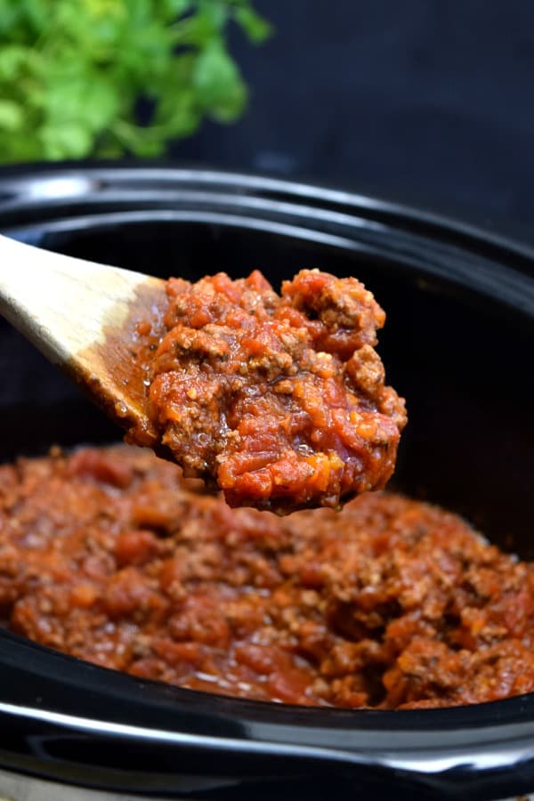 a large spoon full of bolognese sauce over top a crockpot
