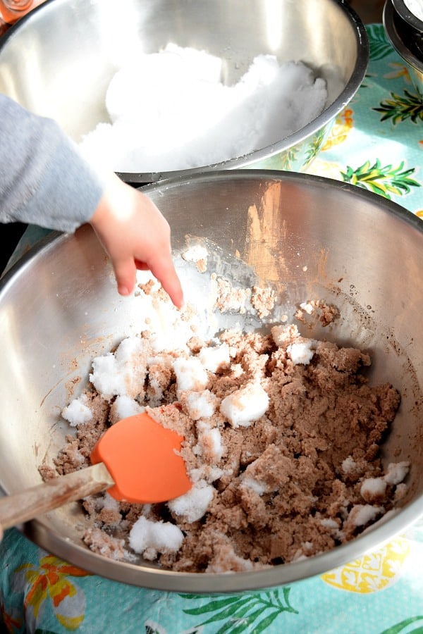 a toddler mixing chocolate snow ice cream together