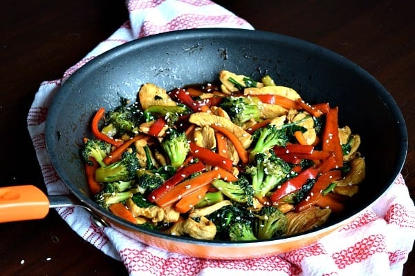 a large skillet filled with chicken, peppers, carrots, and broccoli stir fried together