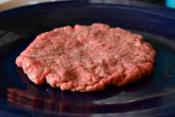 ground beef smashed into a burger patty ready to be grilled