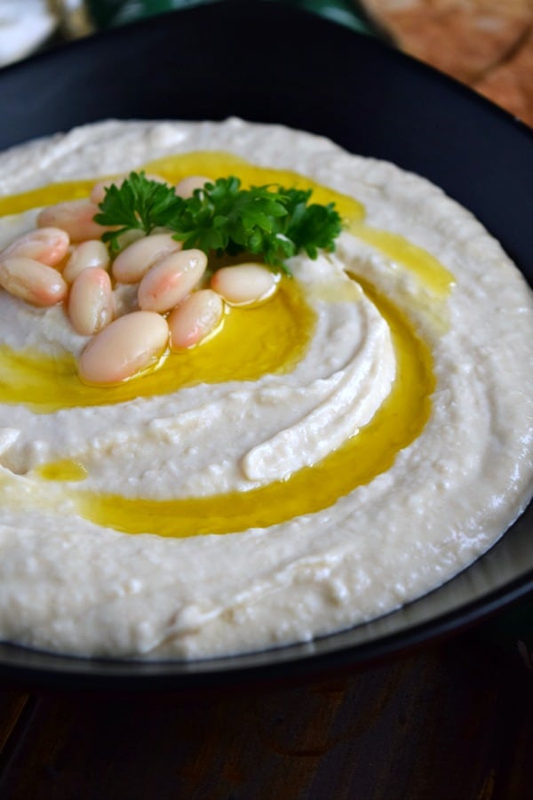 Roasted Garlic White Bean Hummus covered in olive oil, white beans, and parsley 