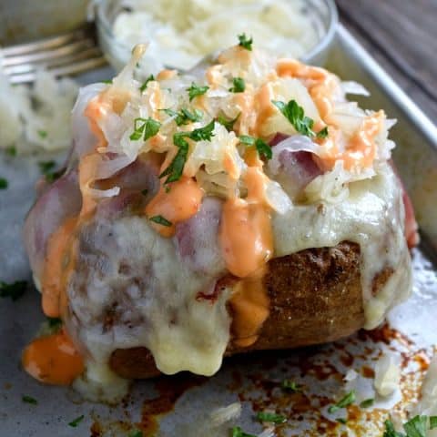Reuben Stuffed Baked Potato covered with sauerkraut and dripping with 1,000 island dressing
