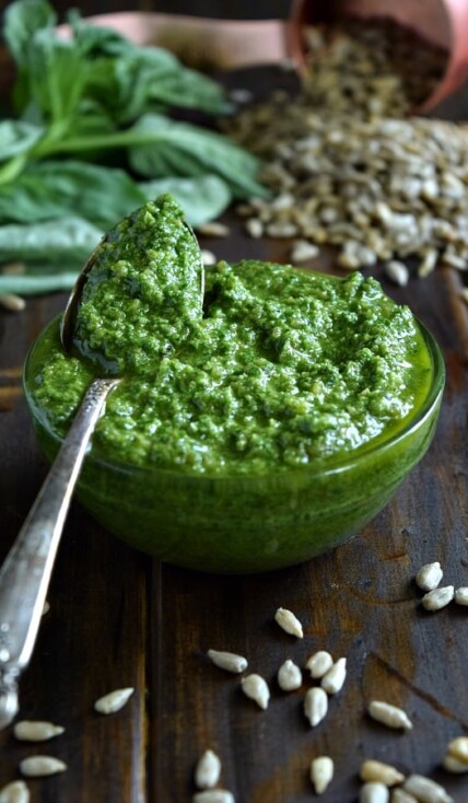 Sunflower Seed Basil Pesto in a small bowl with a spoonful ready to be spread and tossed with your next meal