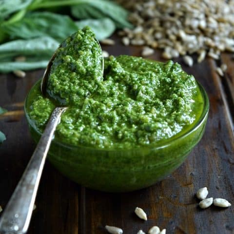 Sunflower Seed Basil Pesto in a small bowl with a spoonful ready to be spread and tossed with your next meal