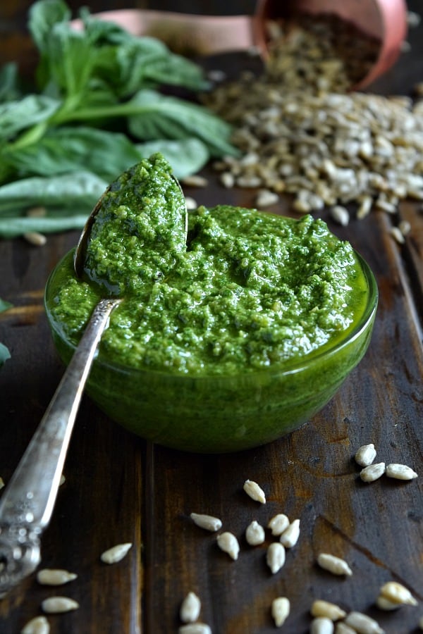 Sunflower Seed Basil Pesto in a small bowl with a spoonful ready to be spread and tossed with your next meal