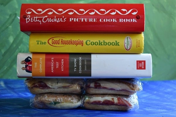 Italian Pressed Picnic Sandwich being pressed down by large cookbooks