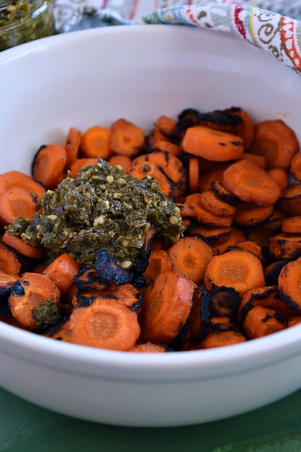 a bowl of grilled carrots with a dollop of pesto ready to toss for Pesto Grilled Carrots Recipe