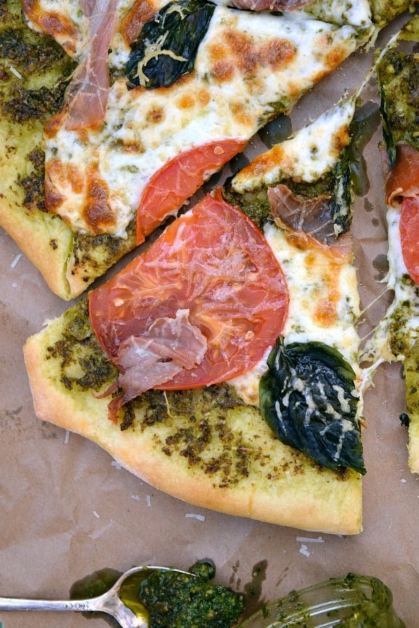 a slice of Pesto Pizza with Prosciutto, Tomatoes, and Mozzarella