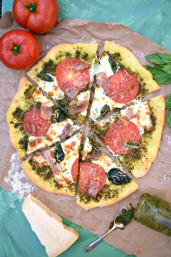 Pesto Pizza with Prosciutto, Tomatoes, and Mozzarella with 6 slices ready to be eaten