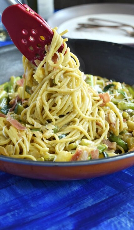 Summer Spaghetti Carbonara being pulled out of a large skillet showing the pasta covered in creamy carbonara sauce