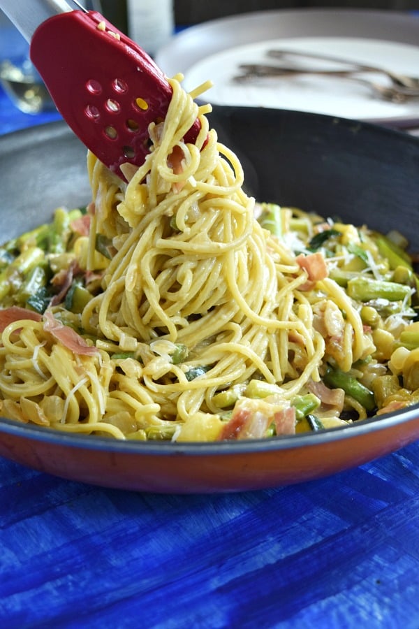 Summer Spaghetti Carbonara being pulled out of a large skillet showing the pasta covered in creamy carbonara sauce