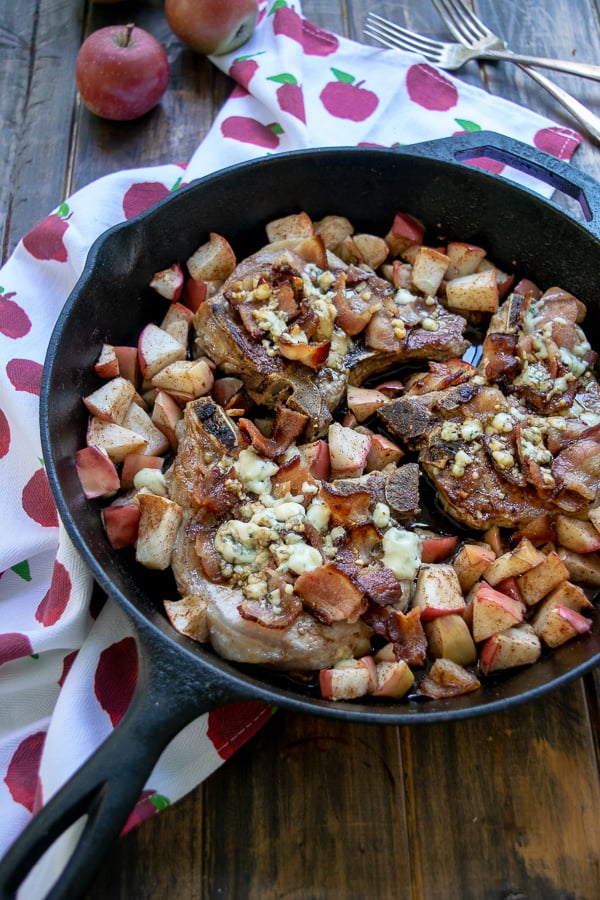 a cast iron skillet full of 3 Apple Bacon Blue Covered Pork Chops
