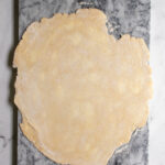 Pinterest pin with image of all butter pie crust rolled out on a marble slab.