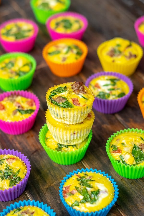 Stack of three spinach sausage egg muffins in colorful silicone liners