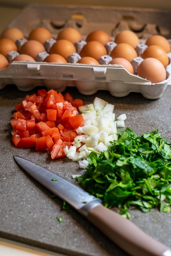 chopped tomato, onion, and spinach on a cutting board